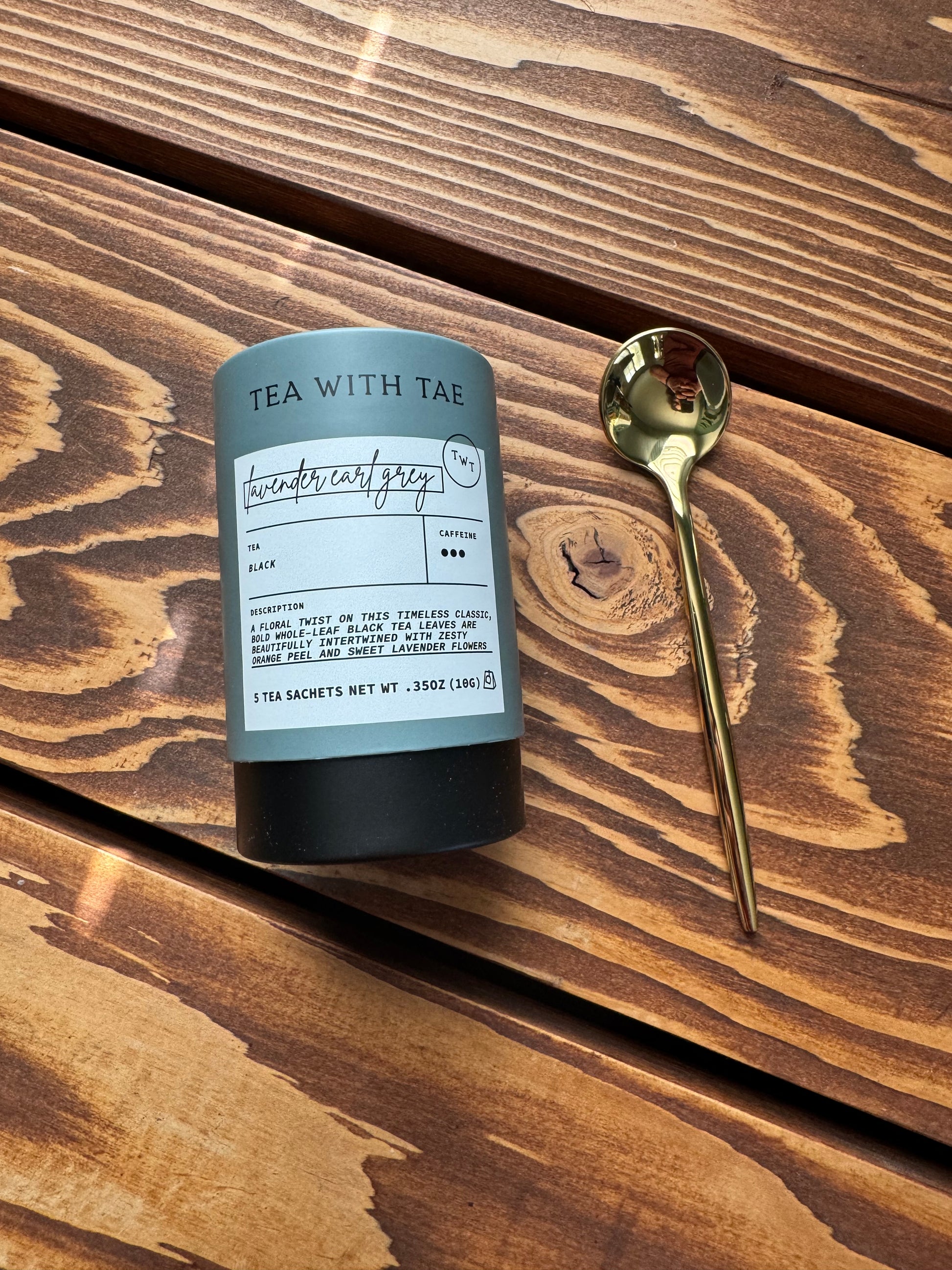 Close up view of the Lavender Earl Grey tea from Tea with Tae and a gold teaspoon on a wood surface